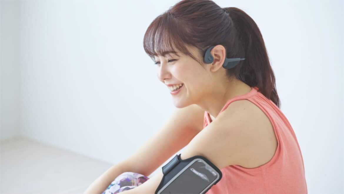 une femme souriante avec un casque à conduction osseuse