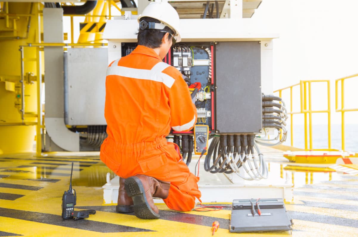 Electricien en orange réparant un équipement